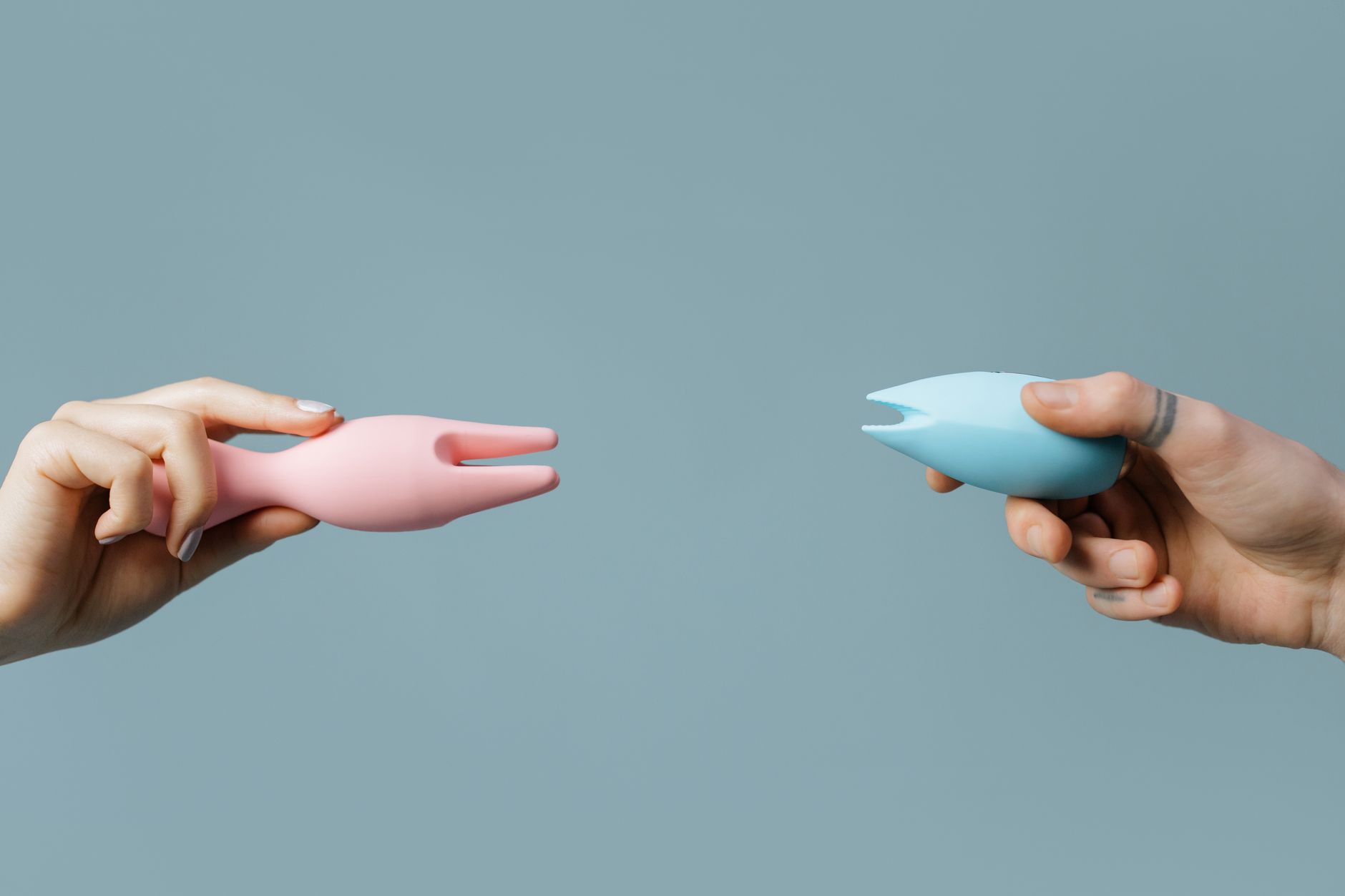 Hand holding an orange vibrator against a minimalistic purple backdrop