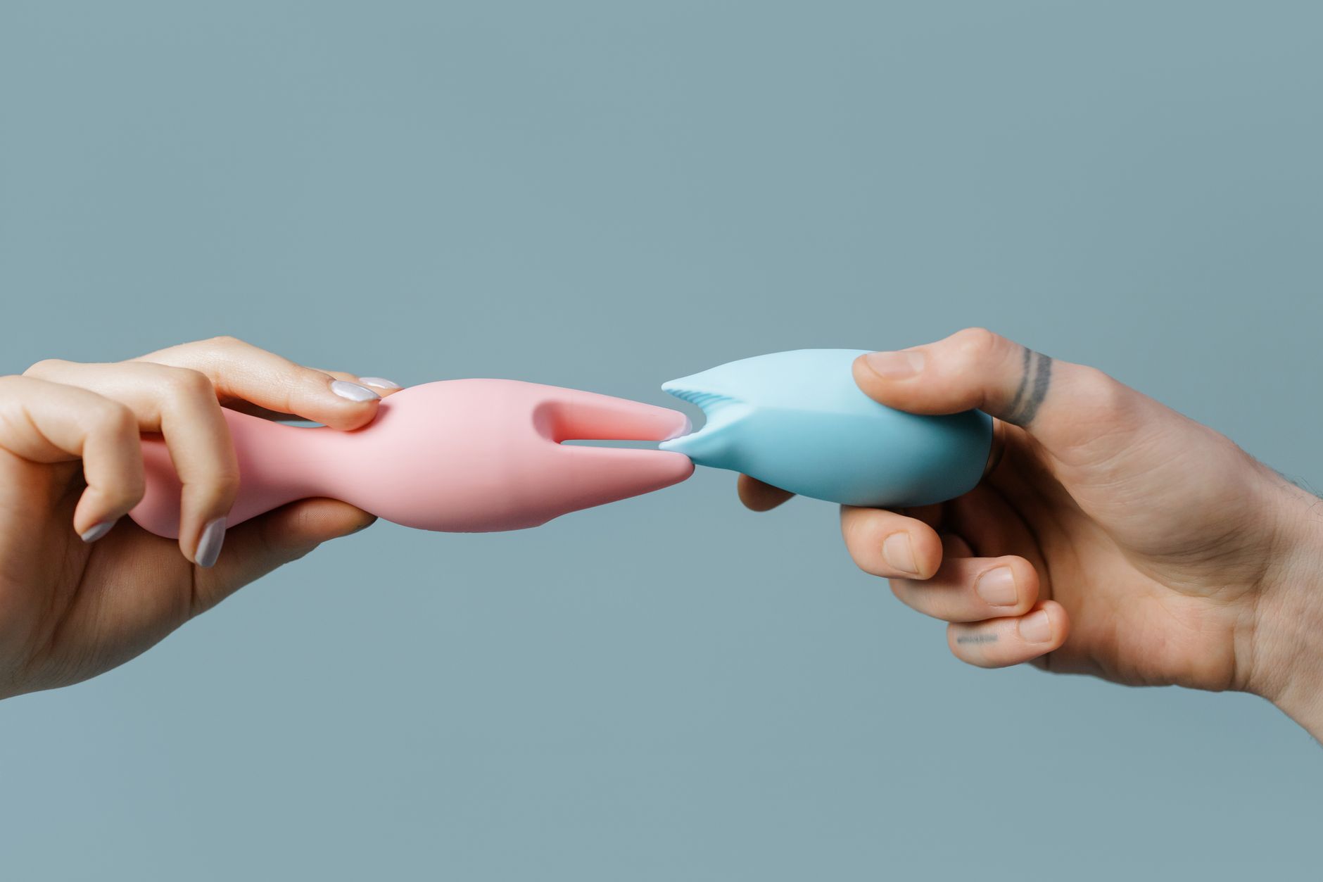 Hands holding colorful silicone toys together, symbolizing shared pleasure in new relationships